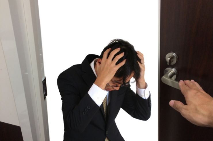 玄関前で頭をかかえる男性